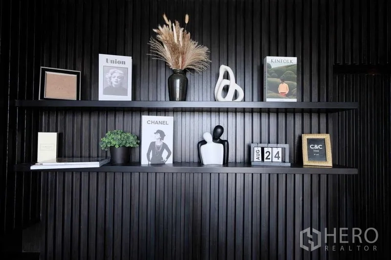 Condominium for sale - Decorative shelving on a black slat wall with books and art pieces.