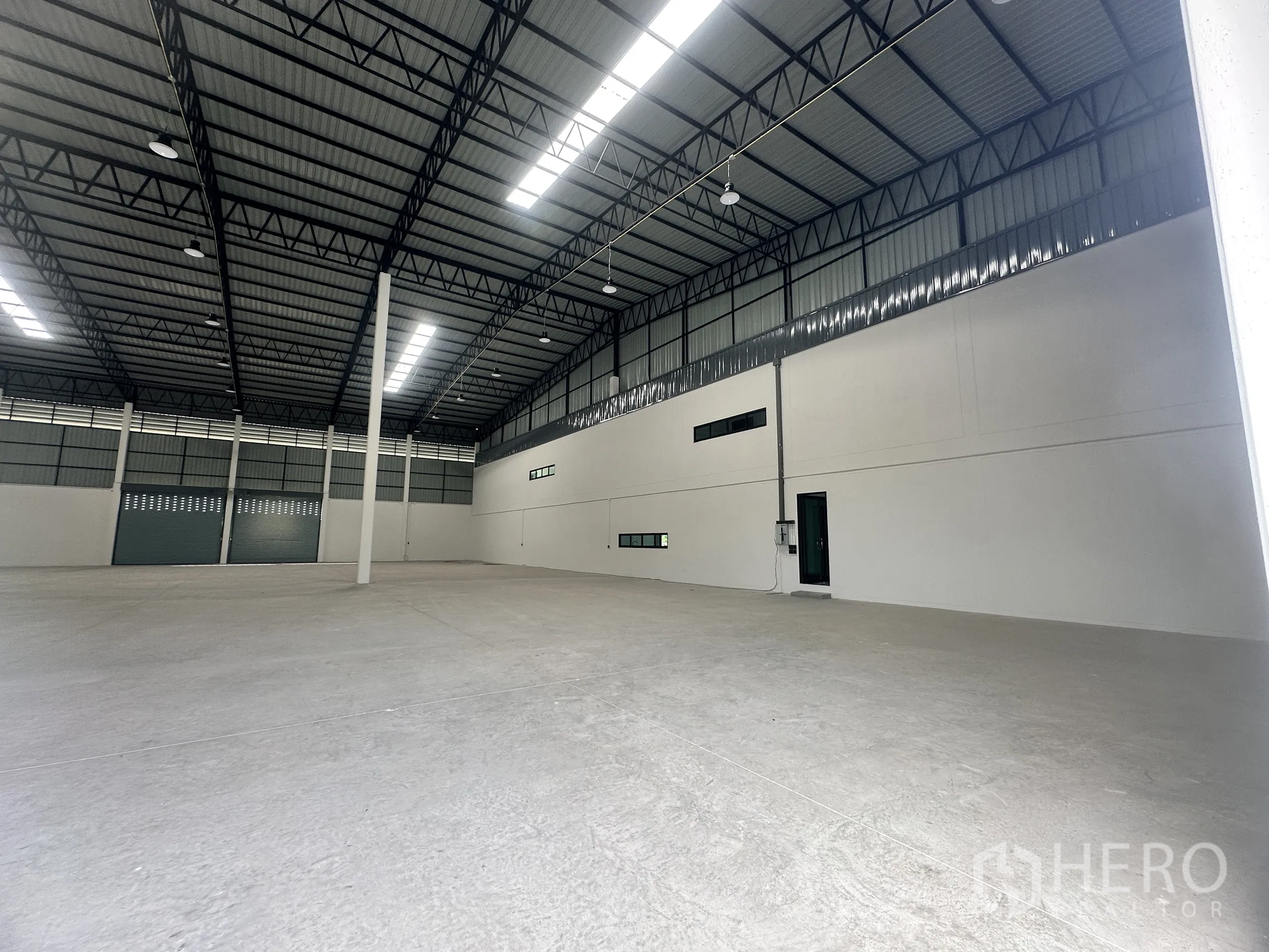 工厂 for rent or sale in Bang Len, Nakhon Pathom - 仓库一角，设人员门与小窗，混凝土地面整洁。