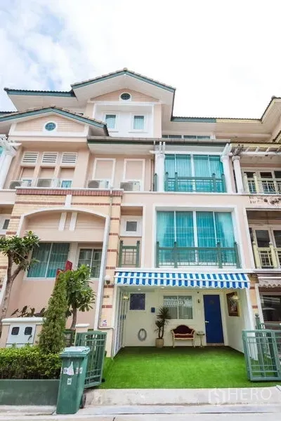 Townhouse for rent in Lat Phrao, Bangkok - Townhouse facade showing striped awning, large windows, gated entrance and neat front garden.