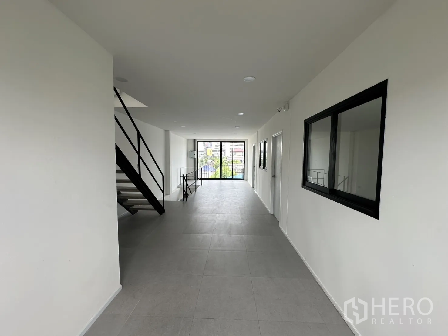 Home Office for rent or sale in Bang Na, Bangkok - Upper-floor corridor with metal staircase and full-height window at the end.