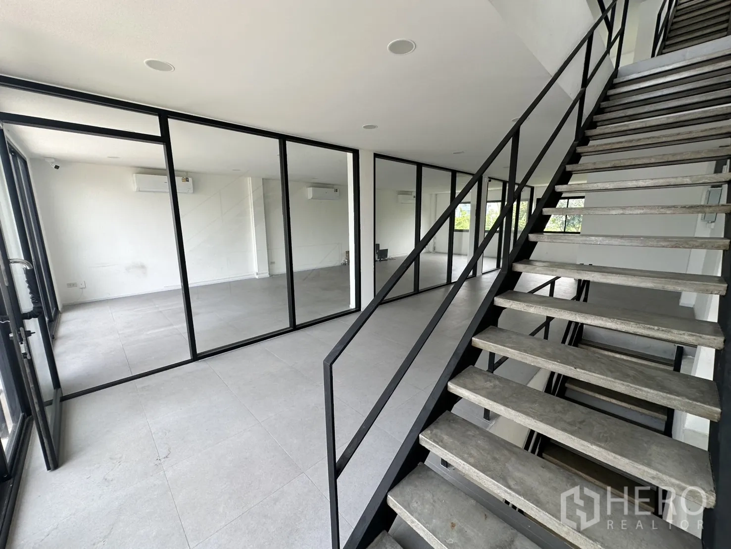 Home Office for rent or sale in Bang Na, Bangkok - Stair landing leading to glass-partitioned rooms with black metal frames.