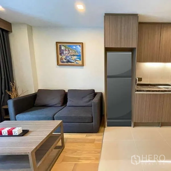 Condominium for rent - Cozy living area beside a compact kitchenette with fridge and sofa.