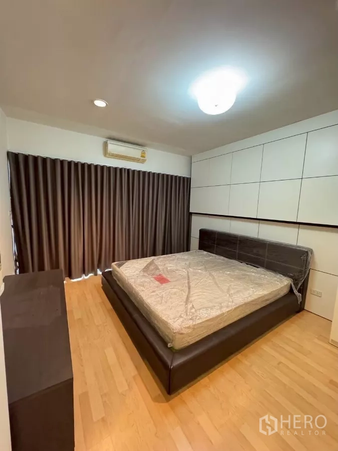 Townhouse for rent in Suan Luang, Bangkok - Master bedroom with king bed, wall cabinetry and full-height curtains.
