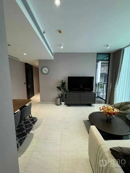 Condominium for rent in Bang Rak, Bangkok - Living room with TV, round coffee tables and access to the balcony