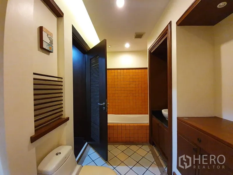 Detached House for rent in Wang Thonglang, Bangkok - Bathroom with bathtub, warm orange tiles, separate vanity and storage niches.