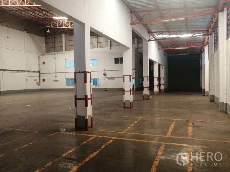 Factory for rent or sale in Bang Phli, Samut Prakan - Spacious warehouse hall with high ceiling, steel truss roof, columns and marked loading zones.