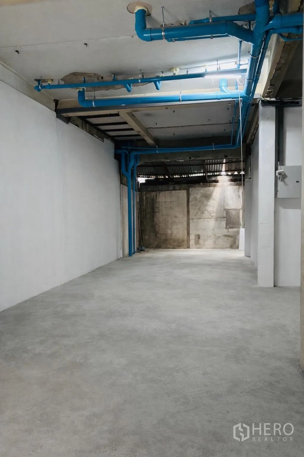 零售空间 for rent in Watthana, Bangkok - 室内开阔空间，水泥地面、白色墙体与蓝色外露管线。