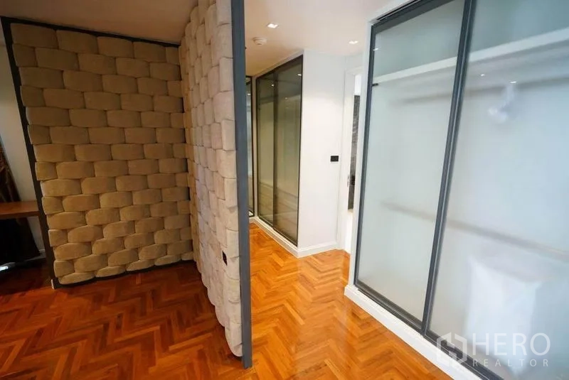 Condominium for rent or sale in Bang Na, Bangkok - Hallway with textured feature wall, sliding wardrobes and polished parquet floor.