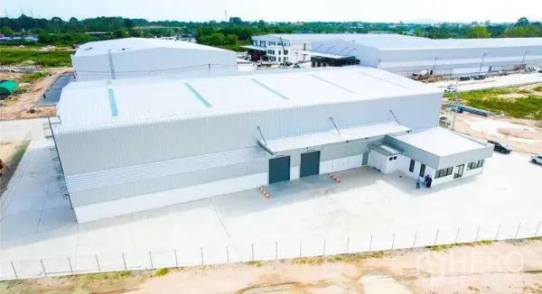 Warehouse for rent in Mueang Rayong, Rayong - Aerial view of a new steel‑clad warehouse with covered loading bays, attached office and fenced concrete yard.