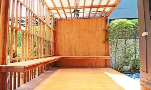 Detached House for rent in Bang Khae, Bangkok - Wooden pergola terrace with built-in bench seating beside landscaped greenery.