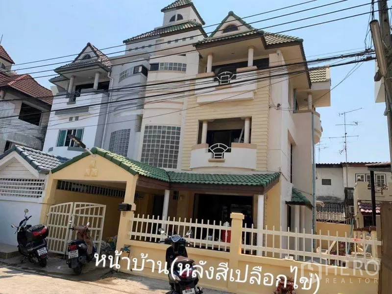Townhouse for rent in Phra Khanong, Bangkok - Three-storey townhouse facade with green tile roof, balconies, and a front gate.