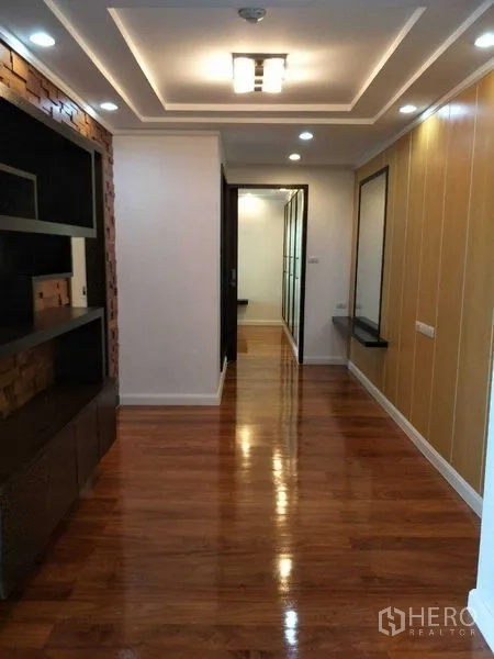 公寓 出租或出售在Watthana, Bangkok - 走廊带造型吊顶与嵌灯，内置展示柜通往卧室区域。