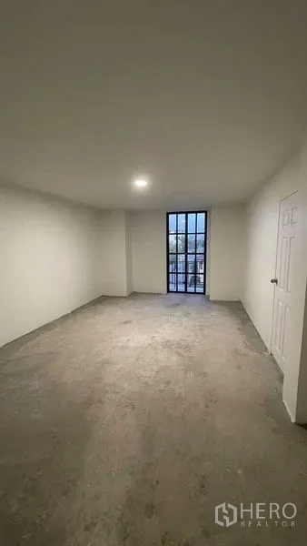Townhouse for sale in Prawet, Bangkok - Spacious bedroom with a floor-to-ceiling window and door to a balcony.