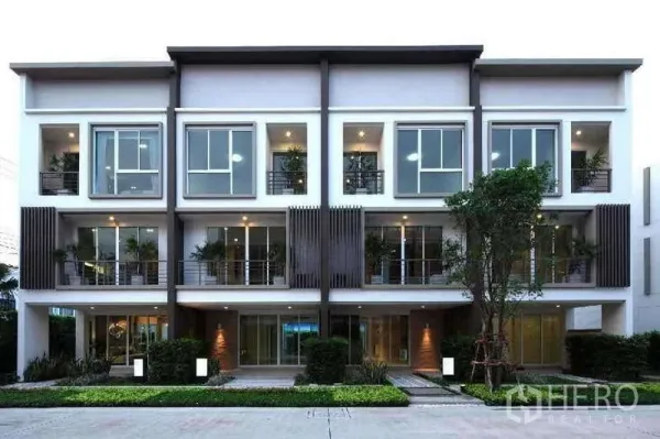 Home Office for rent in Chatuchak, Bangkok - Row of modern three-storey townhomes with landscaped frontage at dusk.