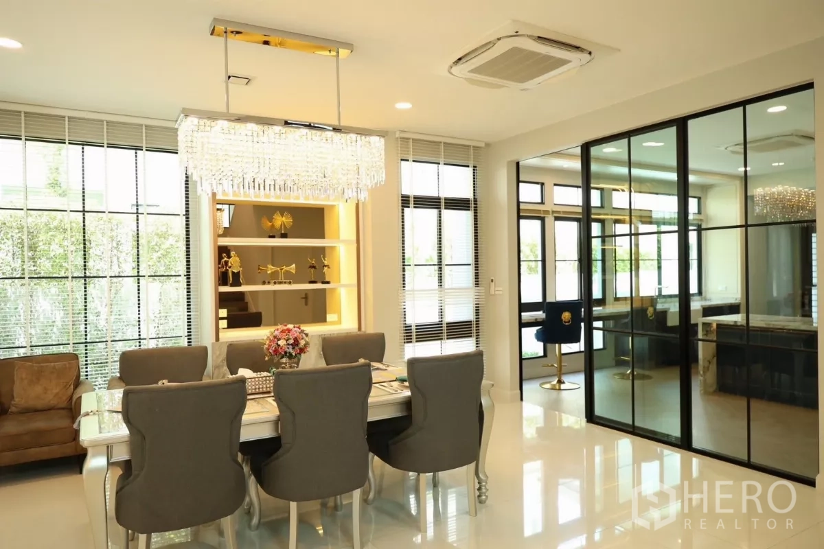 Detached House for rent or sale in Saphan Sung, Bangkok - Dining area under a crystal chandelier with glass partition leading to a separate room.