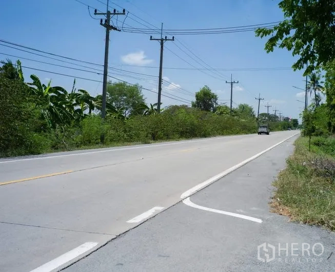 Factory for rent in Pathum Thani - Two-lane concrete road with power lines and greenery near the factory location.