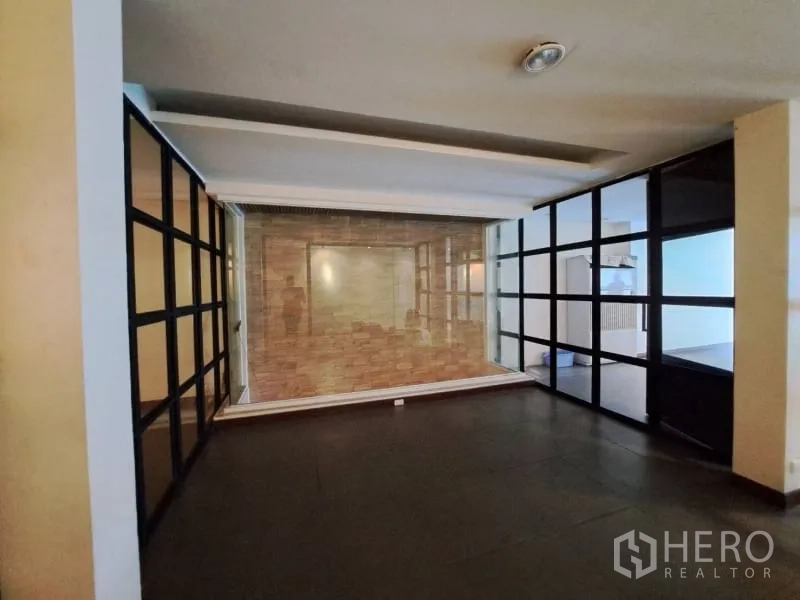 Shophouse for rent in Watthana, Bangkok - Area with floor-to-ceiling glass partitions and a stone feature wall.