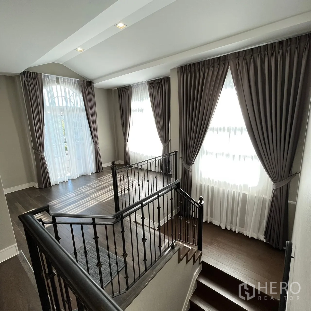 Detached House for rent or sale in Bang Khen, Bangkok - Upper landing with iron staircase railing and tall curtained windows.