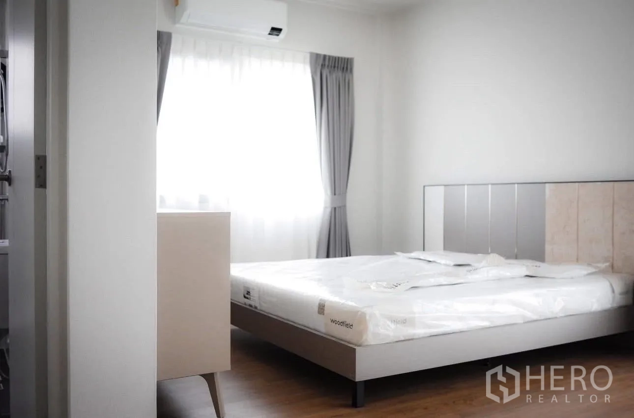 Detached House for rent in Bang Phli, Samut Prakan - Sunlit bedroom with bed, grey curtains, and wall-mounted air conditioner.