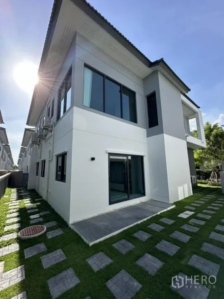 Detached House for rent in Bang Phli, Samut Prakan - Rear corner of the house with lawn, stepping stones, and expansive windows.