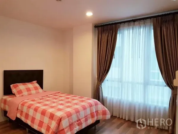 Condominium for rent in Phaya Thai, Bangkok - Second bedroom with a single bed, full-length curtains and warm wood floors.