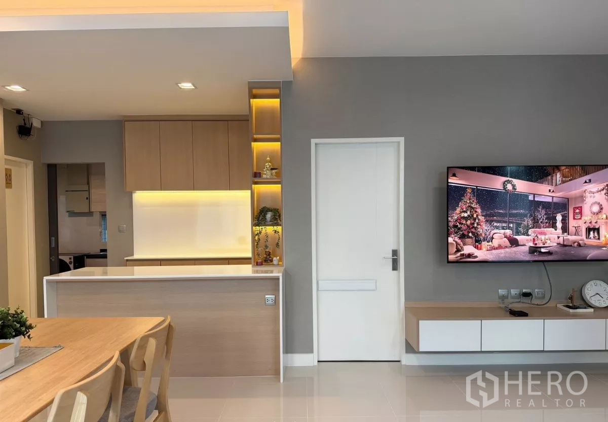 独立式住宅 出租在Prawet, Bangkok - 电视背景墙与暖光展示层架，邻近小型吧台厨房
