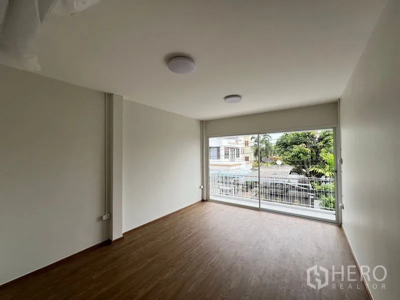 带办公室的家 出租在Huai Khwang, Bangkok - 卧室配整面落地窗与阳台栏杆，俯瞰绿意。