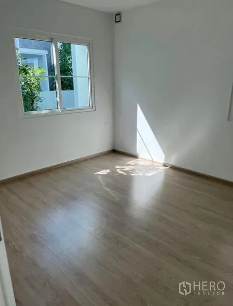 独立式住宅 出租在Min Buri, Bangkok - 采光充足的卧室，木纹地板，窗外可见绿植。
