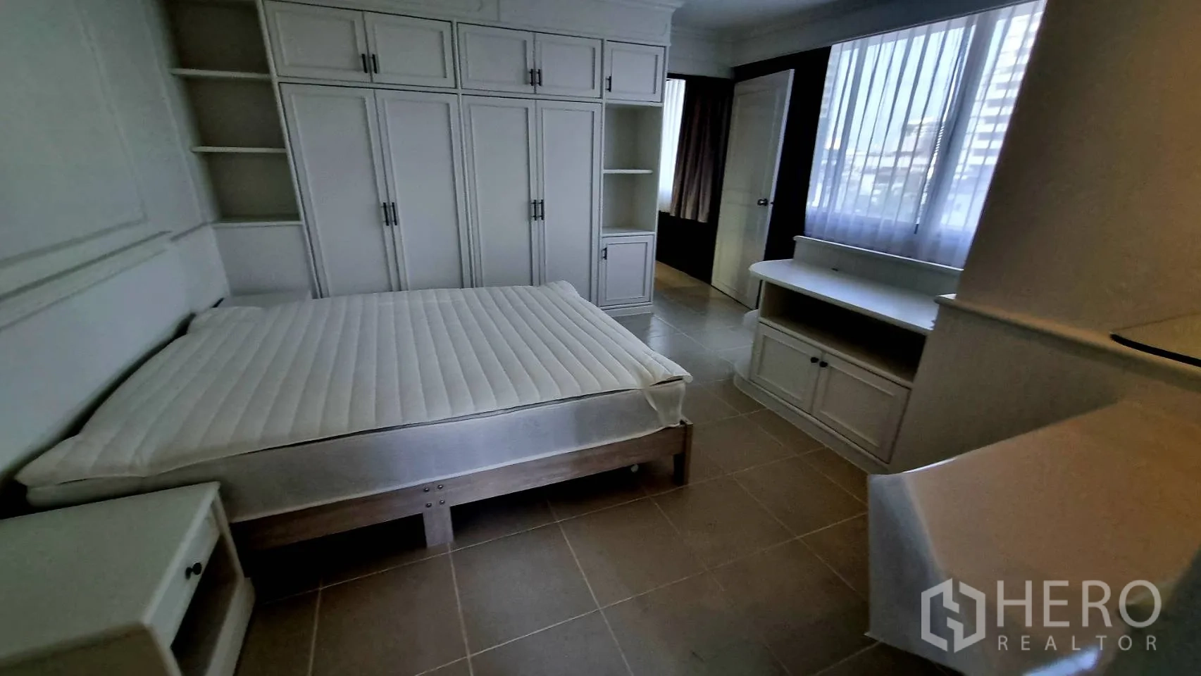 Condominium for rent in Watthana, Bangkok - Bright bedroom with large window and built-in console.