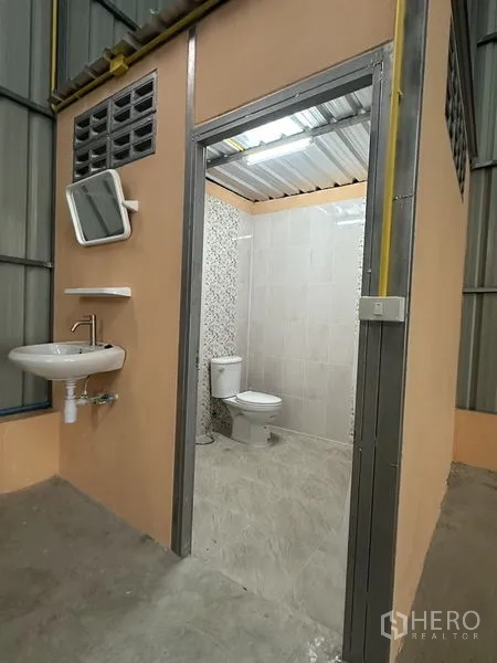 Warehouse for rent in Bueng Kum, Bangkok - Clean warehouse restroom with toilet, tiled walls and washbasin.