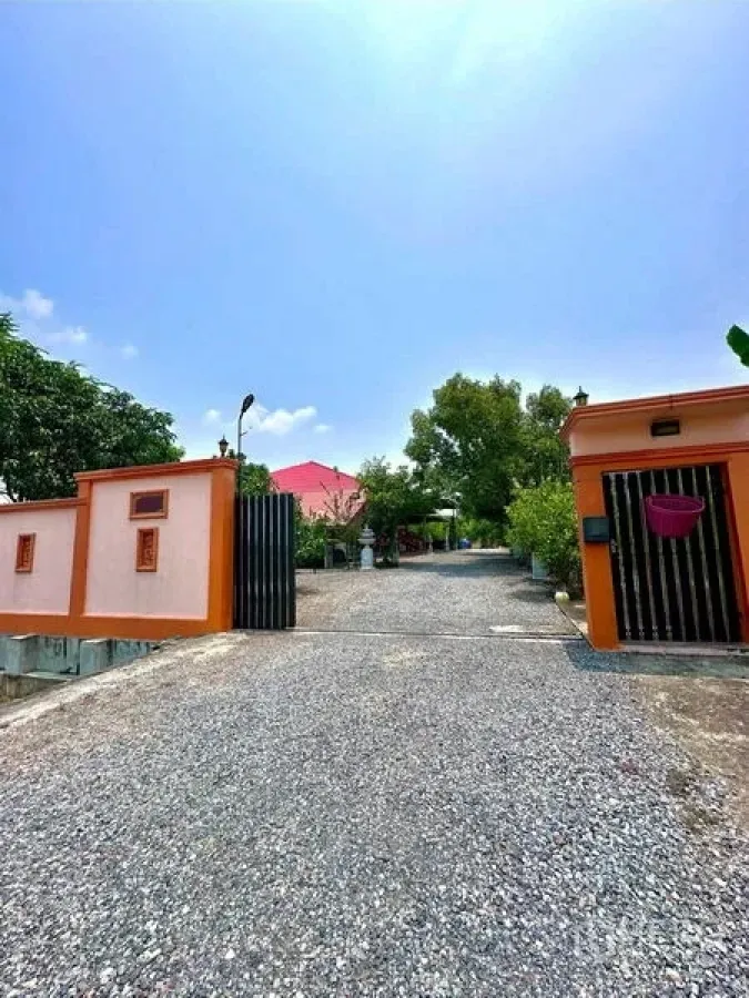Detached House for sale in Bang Bua Thong, Nonthaburi - Front gate and wide driveway framed by trees on a sunny day.