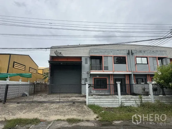 Warehouse for rent or sale in Bang Yai, Nonthaburi - Gated two-storey warehouse facade with large roller shutter and parking apron in Bang Yai, Nonthaburi.