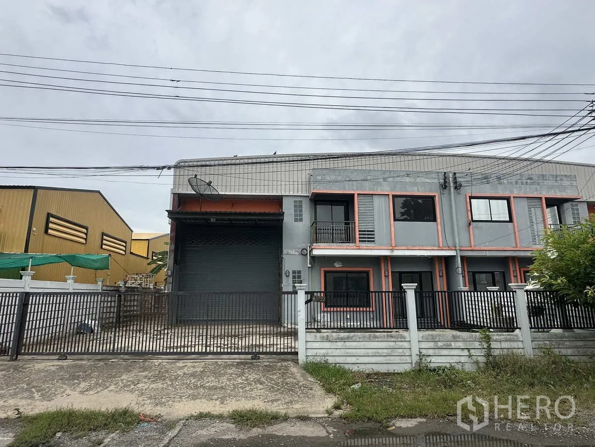 Warehouse for rent or sale in Bang Yai, Nonthaburi - Gated two-storey warehouse facade with large roller shutter and parking apron in Bang Yai, Nonthaburi.