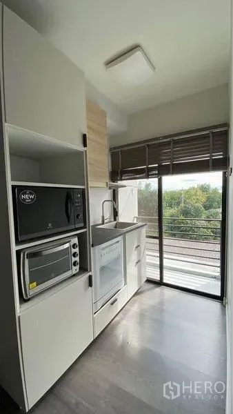 Retail Space for sale in Bang Na, Bangkok - Compact pantry with built‑in microwave, oven and sink beside a sliding glass door with green views.