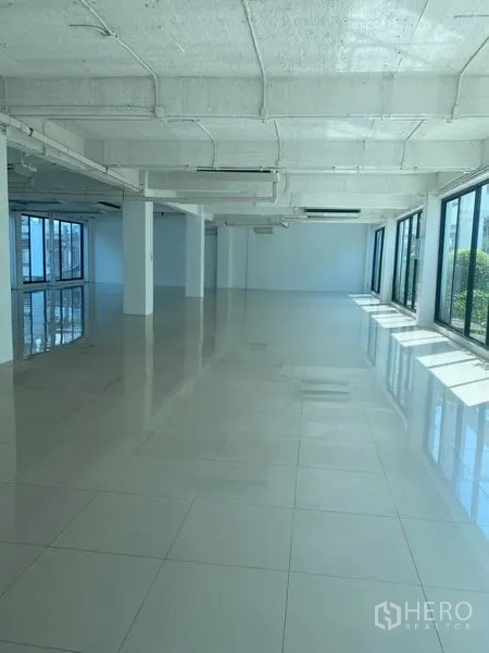 办公空间 出租在Khlong Toei, Bangkok - 宽敞工作区，柱体与全景窗，瓷砖地面与外露管线。