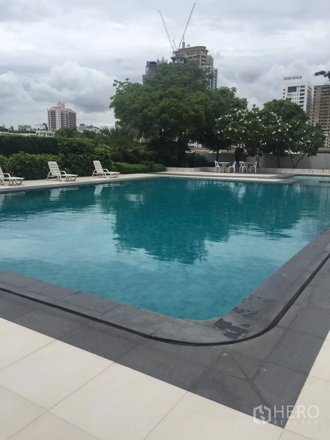 公寓 出租在Watthana, Bangkok - 室外游泳池设躺椅，可观城市景观与绿化。