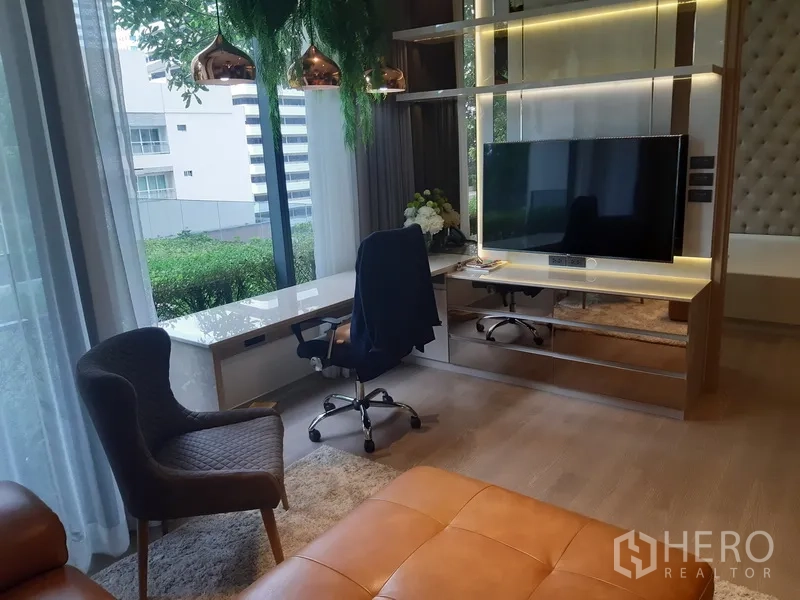 公寓 出租或出售在Watthana, Bangkok - 带LED灯带的内置电视墙与长条窗边书桌，可眺望绿意。
