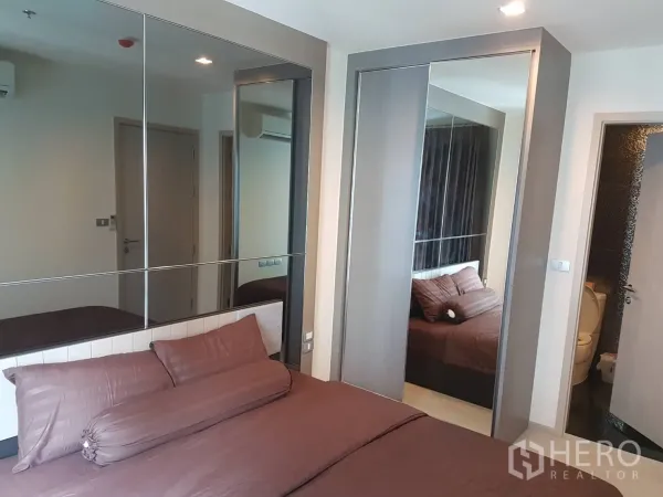 公寓 出租在Khlong Toei, Bangkok - 卧室以棕色床品为主，带镜面墙与推拉衣柜。