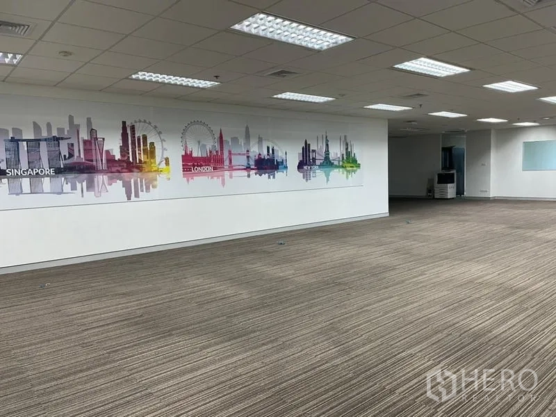 สำนักงาน ให้เช่า - พื้นที่ออฟฟิศโอเพ่นกว้าง ปูพรม ฝ้าเพดานทีบาร์ ไฟสว่าง และภาพกราฟิกสกายไลน์บนผนัง