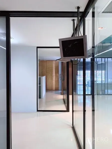 办公空间 出租在Phaya Thai, Bangkok - 玻璃墙走廊，黑色框架与悬挂显示器，通往会议室与私人空间。