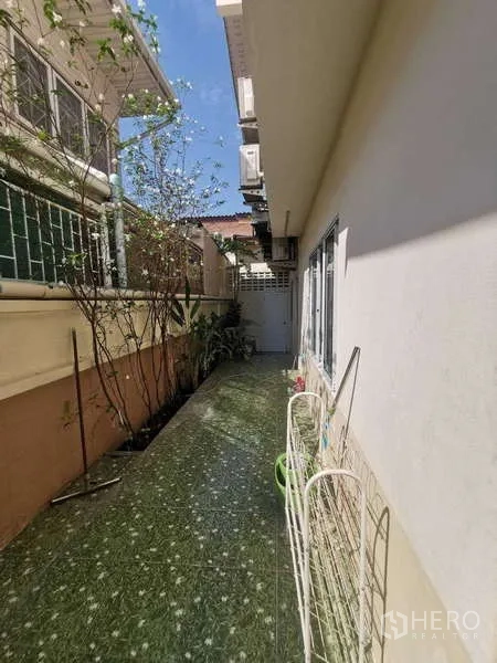 Townhouse for rent in Chatuchak, Bangkok - Narrow side yard with tiled walkway and planter bed along the wall.