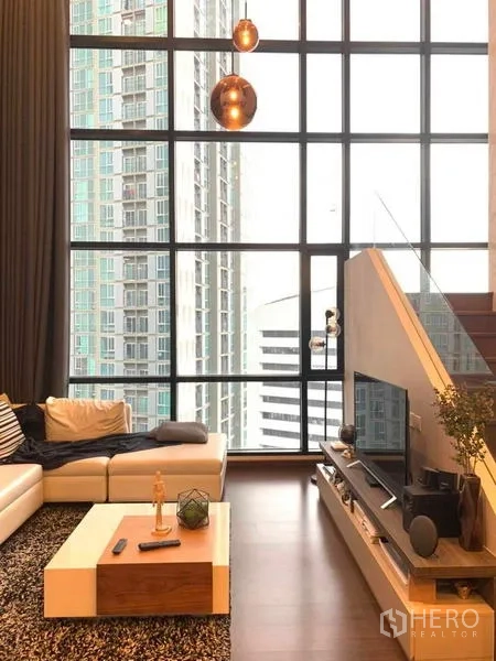คอนโด ให้เช่าหรือขายในHuai Khwang, Bangkok - ห้องนั่งเล่นเพดานสูง หน้าต่างบานใหญ่และบันได วิวเมือง