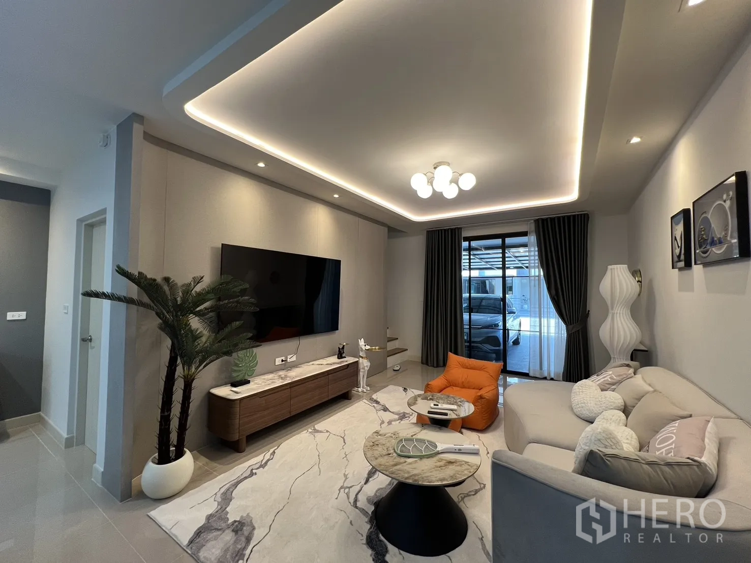 联排别墅 for rent in Bang Phli, Samut Prakan - 客厅面向推拉门与车棚，配窗帘与特色照明。