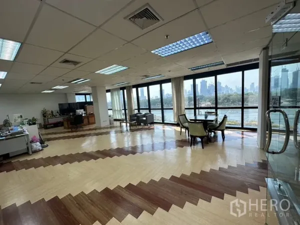 办公空间 出租在Khlong Toei, Bangkok - 宽敞的开放式办公室，落地窗俯瞰 Benjakitti 公园湖景与曼谷天际线，窗边设有会客区。