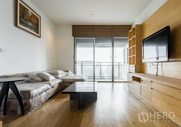 公寓 出租在Watthana, Bangkok - 明亮客厅，转角沙发，推拉落地门通阳台，配内置电视柜。