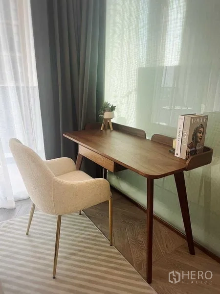Condominium for rent in Khlong Toei, Bangkok - Work corner with wooden desk and upholstered chair by the window.