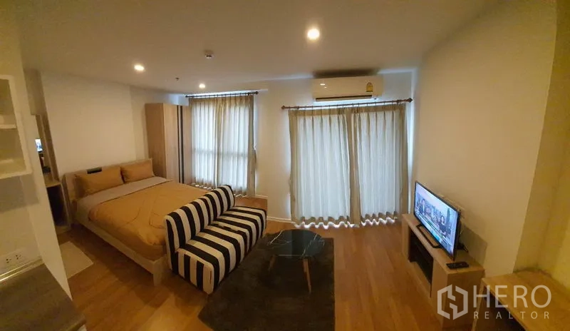 公寓 出售在Chatuchak, Bangkok - 类似单间布局，展示床、沙发、两扇窗与电视的乍都节公寓。