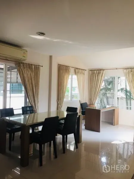 Detached House for rent in Bang Kapi, Bangkok - Bright dining and study area with glass table, cream curtains and corner windows overlooking greenery.