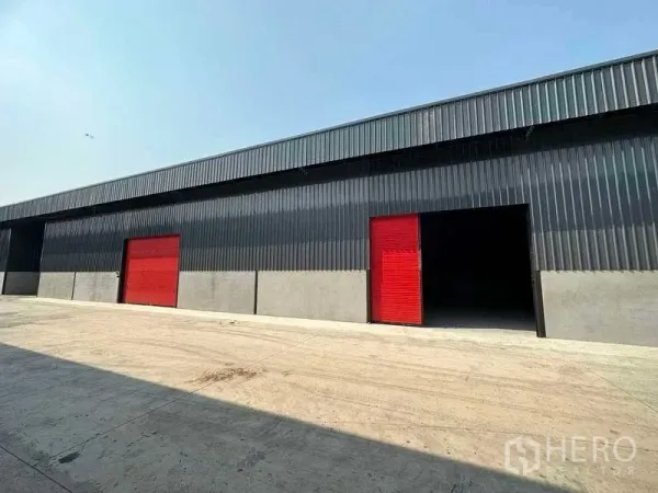 Warehouse for rent in Khlong Sam Wa, Bangkok - Exterior angle of the warehouse with red roller shutters and ample loading apron.