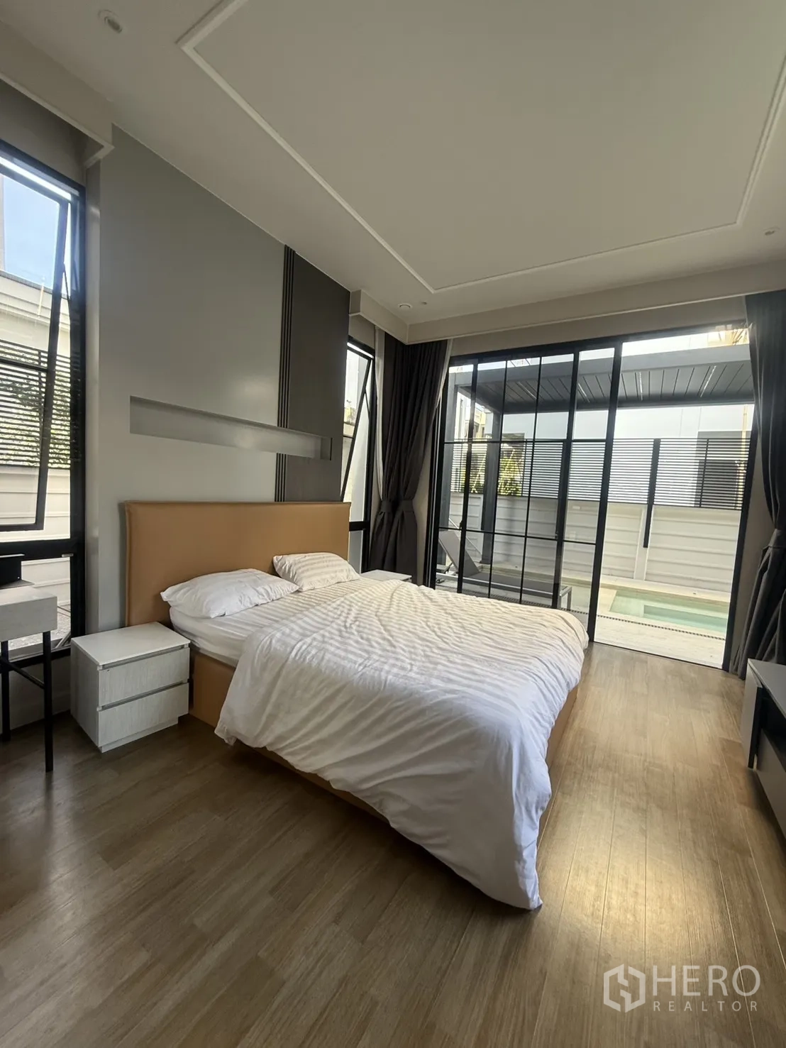 Detached House for rent in Saphan Sung, Bangkok - Bright master bedroom with wood floor, floor-to-ceiling windows and pool view.